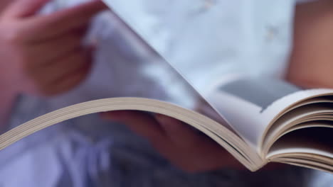 browsing the pages of a picture book, a woman is learning a few things about the illustrations in a book she is reading