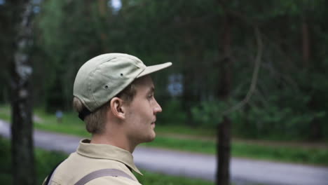 close shot from side of face of young man in cap walking in forest