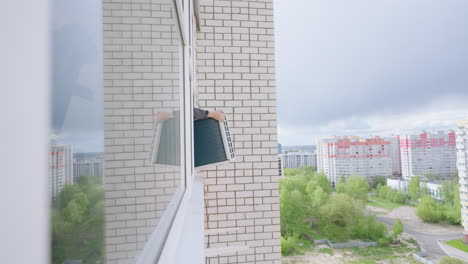 아파트에서 공기 냉각 시스템의 설치 남자 마스터는 에어컨을 창문 밖으로 가져와 높은 고도에서 집 벽에 ugo를 고정. 컨디셔닝 시스템