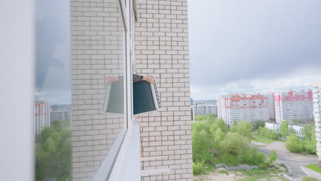 installation of the air cooling system in the apartment the man master takes the air conditioner out the window and fastens the ugo on the wall of the house at a high altitude. conditioning systems