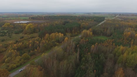 Traktor-Fährt-Auf-Einer-Regionalstraße,-Die-Durch-Den-Herbstlichen-Wald-Führt