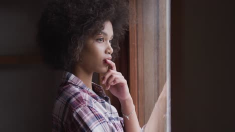 mixed race woman looking through the windows at home