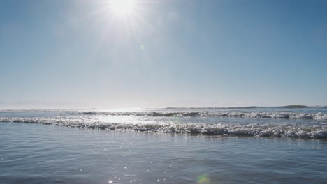 slow motion sequence of waves breaking on shore with lens flare