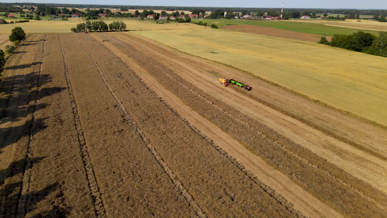 Aerial view showing farm machinery working on agricultural field while sun is shining
