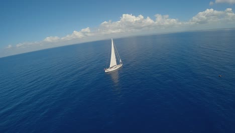 Dynamische-Drohnenaufnahme-Eines-Einsamen-Segelboots-Auf-Dem-Blauen-Karibischen-Meer-An-Einem-Sonnigen-Tag