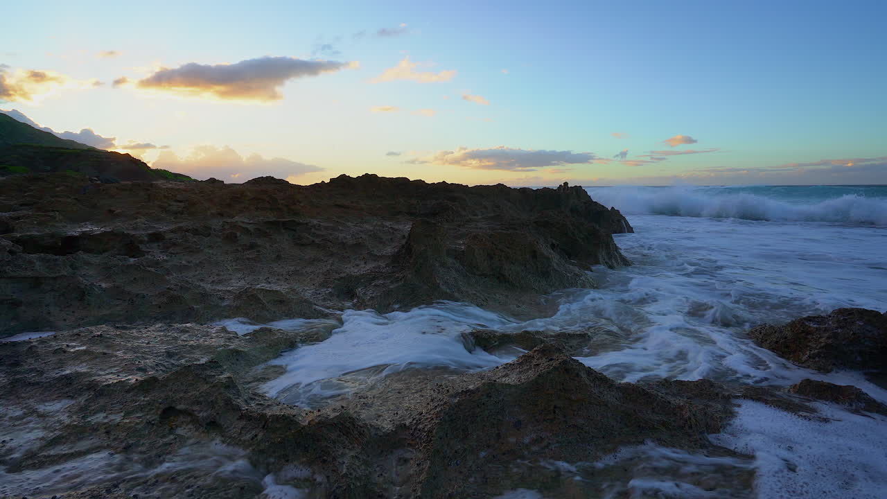 disparo bajo de olas rompiendo contra las rocas en mokuleia rock beach durante la puesta de sol- oahu hawaii