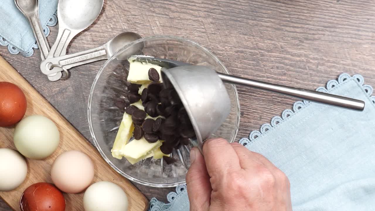 Baking delicious caramel pecan brownies. Adding butter and chocolate chips to a clear mixing bowl. Freshly baked gooey chocolate brownies with sweet caramel and nutty pecans. Eggs and spoons.