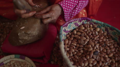 crushing argan seeds by hand with rocks up close pan across