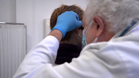 médico que usa otoscopio para examinar los oídos del paciente