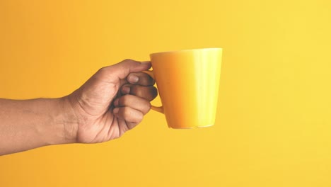 hand holding a yellow cup