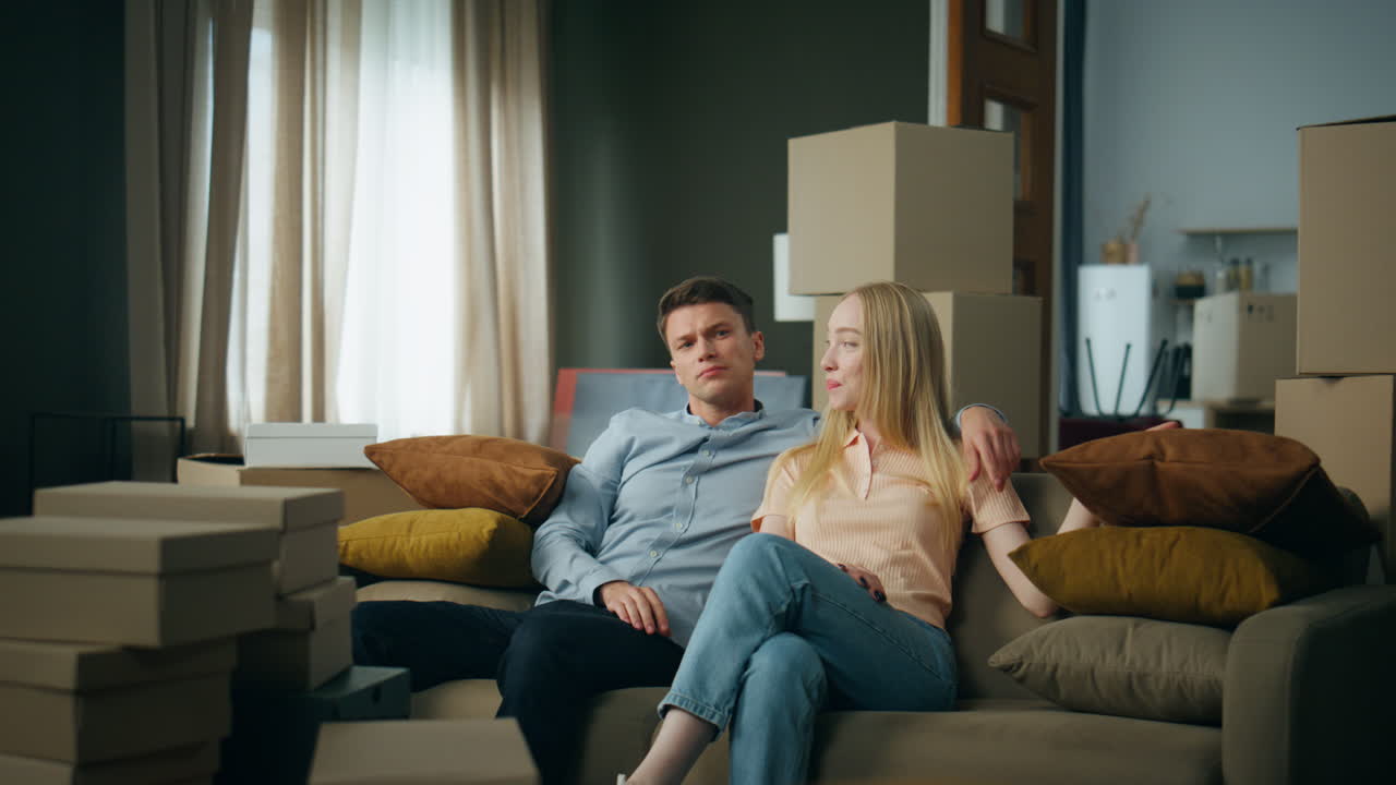 Par kigger på nyt værelse, sidder i sofaen efter flytning. Parret diskuterer indretning.