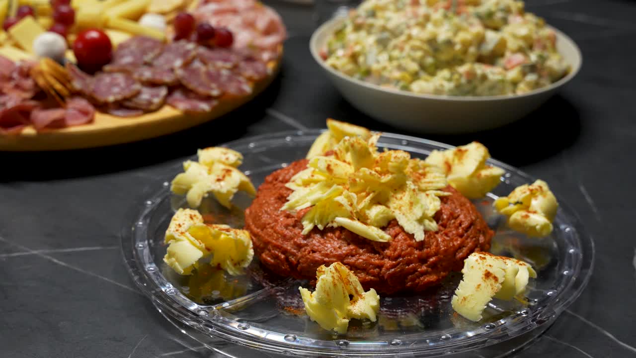 Una festosa cena di Natale con una tartare di manzo gourmet come piatto principale, servita con un contorno di insalata francese tradizionale, formaggi artigianali e salumi pregiati per un banchetto natalizio, vista ravvicinata
