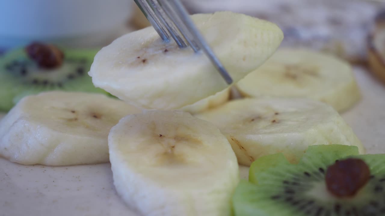 primer plano de plátano cortado y fruta de kiwi en un plato blanco