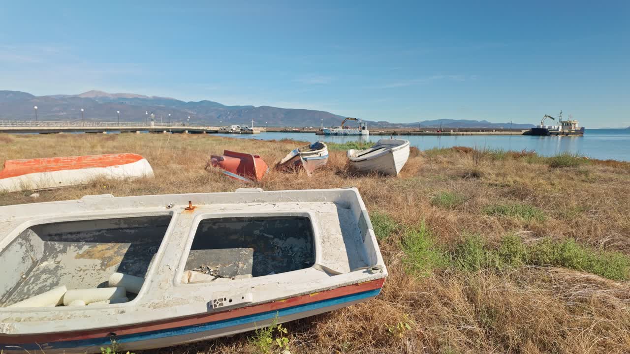Neglected wooden fishing boats abandoned on grassy Greek beach