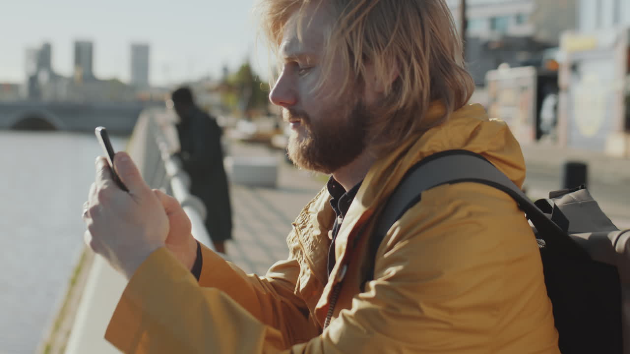 Man Taking Pictures of River with Phone from Urban Embankment