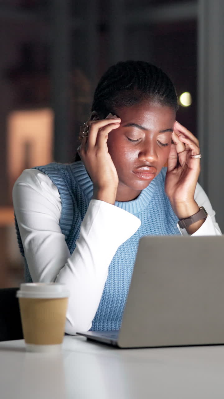 Giovane donna stressata che lavora fino a tardi al laptop in ufficio