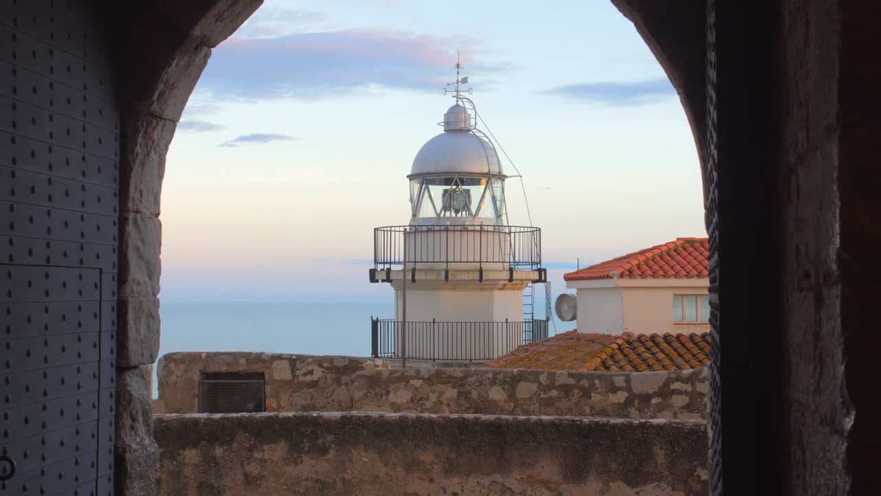 Maják Peníscola viděný z klenutého balkónu ve starém městě Peníscola, Castellón, Španělsko.