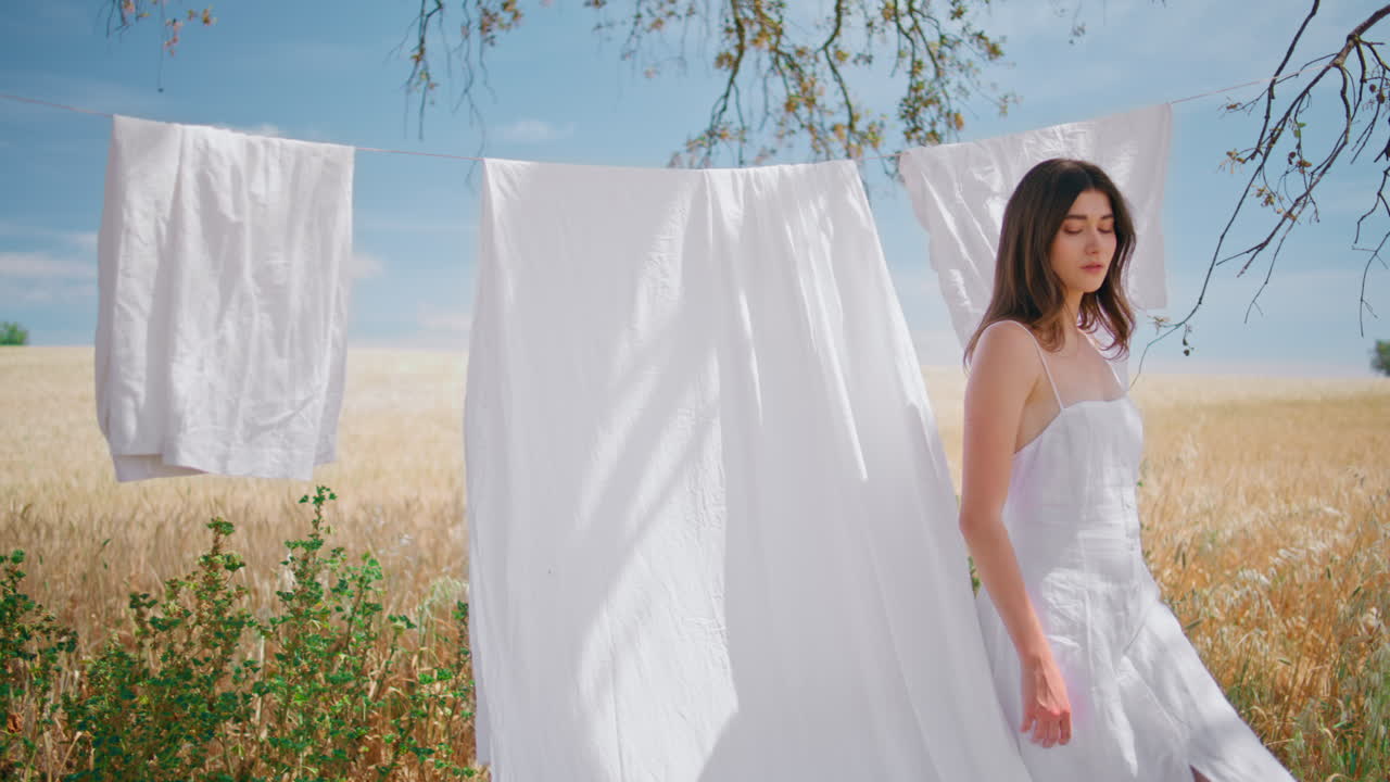 시골 모델이 옷을 고 옷을 건조합니다. 야외에서 매혹적인 여성이 카메라를 찾습니다.