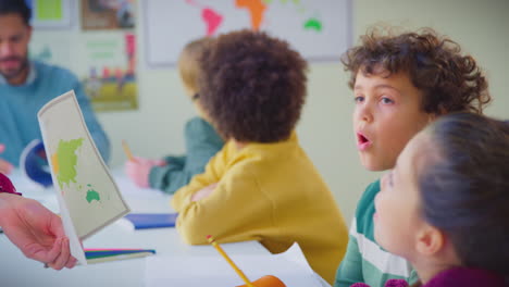 estudiantes de escuela primaria con maestra mirando el mapa en la lección de geografía en el aula