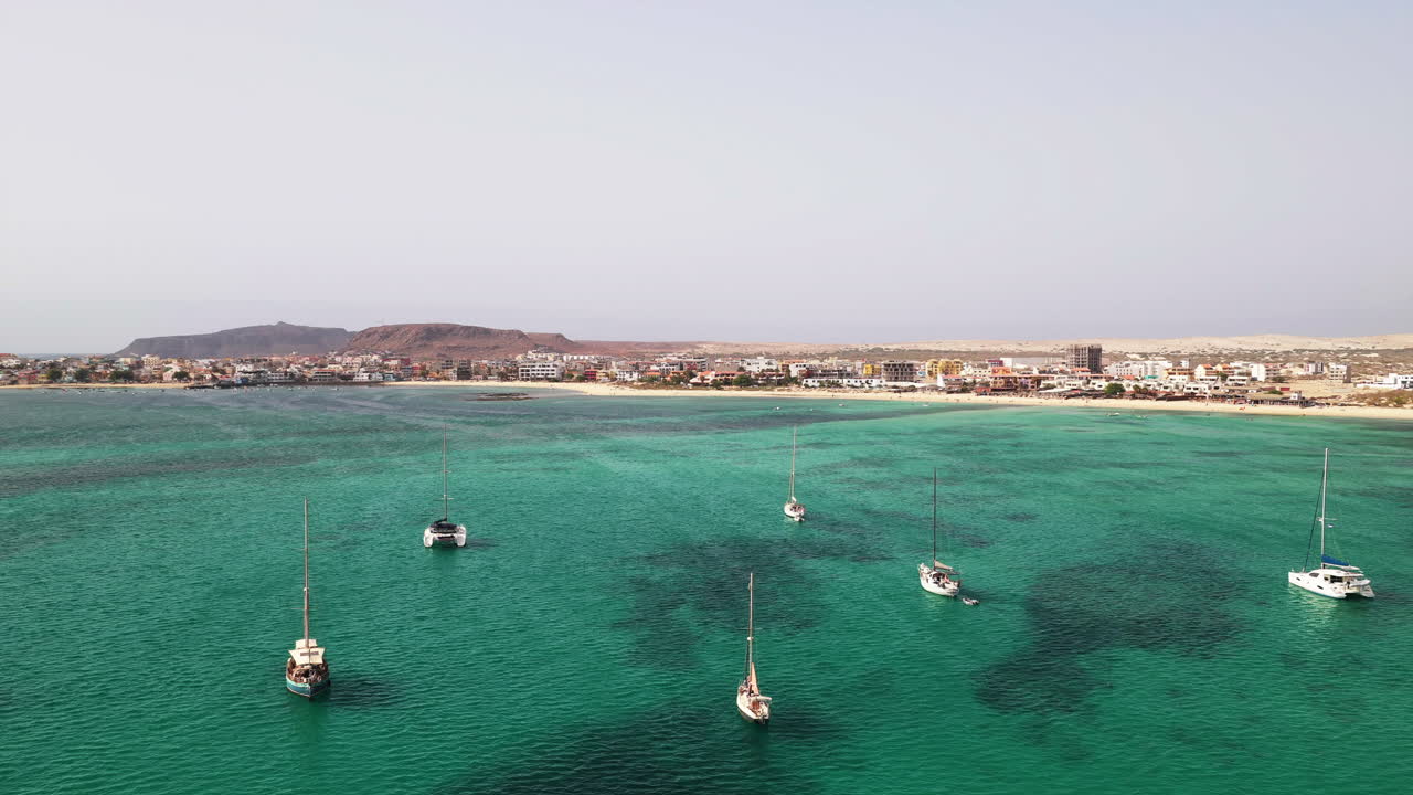 Aerial view of the city of Sal Rei, many luxury yachts moored in turquoise ocean,in front of Sal Rei city and background the desert with the mountains, summer concept