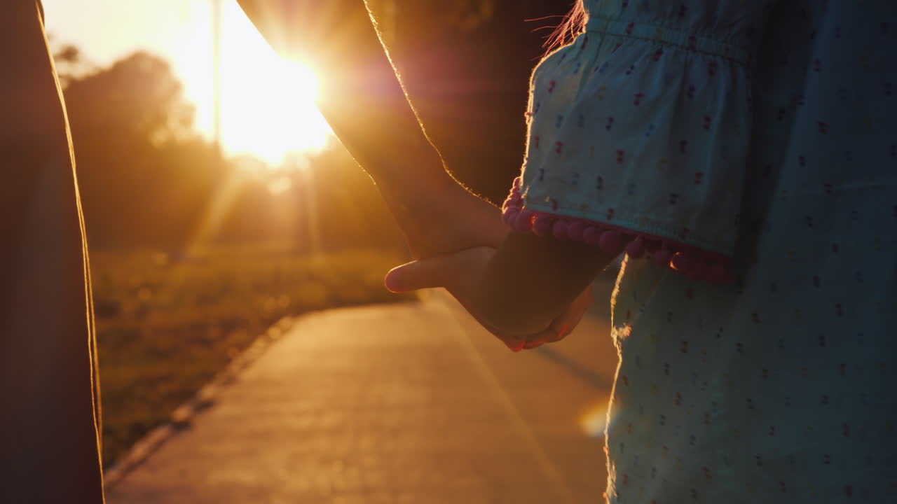 엄마는 석양의 행복한 어린 시절과 부모의 ca에서 골목 아래로 손으로 딸을 인도합니다.