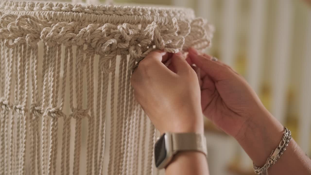 집에서 마크라메를 뜨개질하는 취미. 여성의 손은 두꺼운 가닥으로 장식을 뜨개진다.