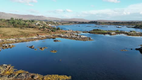 aerial drone track over the shoreline of a rural rocky lake landscape in galway ireland