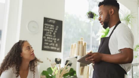 happy african american male barista taking order from biracial female client at cafe