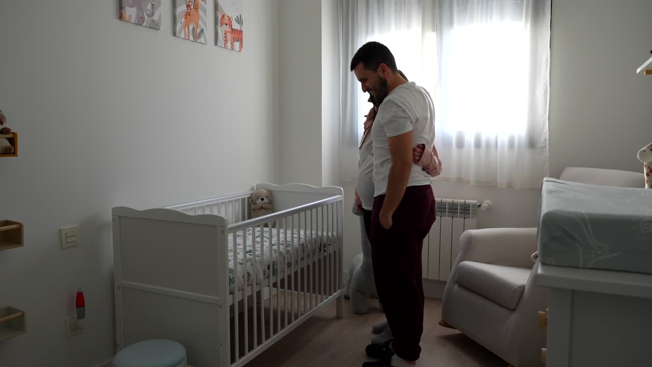 Young pregnant couple checking the room for the future baby