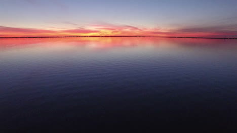 aerial push in and pan up revealing shot of sunset over a calm lake.