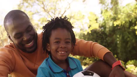 Portrait-of-father-and-son-are-sitting-with-a-soccer-ball-