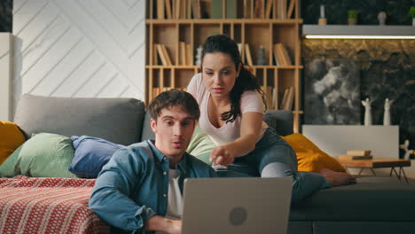 pareja casada usando portátil sentada en el sofá de la sala de estar. familia usando aparatos
