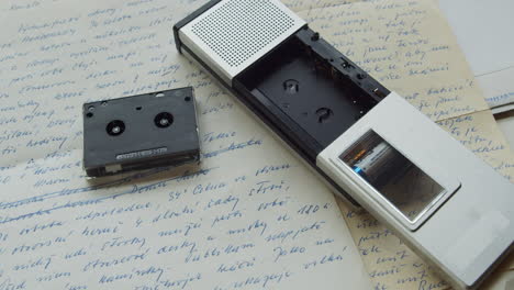 A-micro-cassette-recorder-from-the-1980s,-lying-on-top-of-handwritten-letters