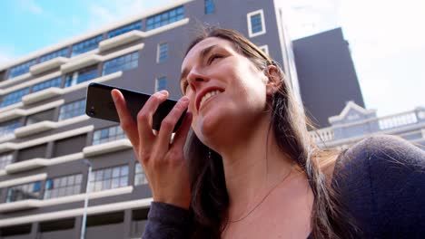 Vista-De-ángulo-Bajo-De-Una-Mujer-Hablando-Por-Teléfono-Móvil-En-La-Ciudad-4k