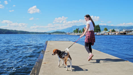 girl walking with her dog along waterfront marina quay in summer, port alberni, british columbia canada