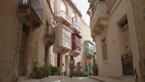 lonely tourist woman walking in a beautiful medieval street in birgu, one of the three cities of malta