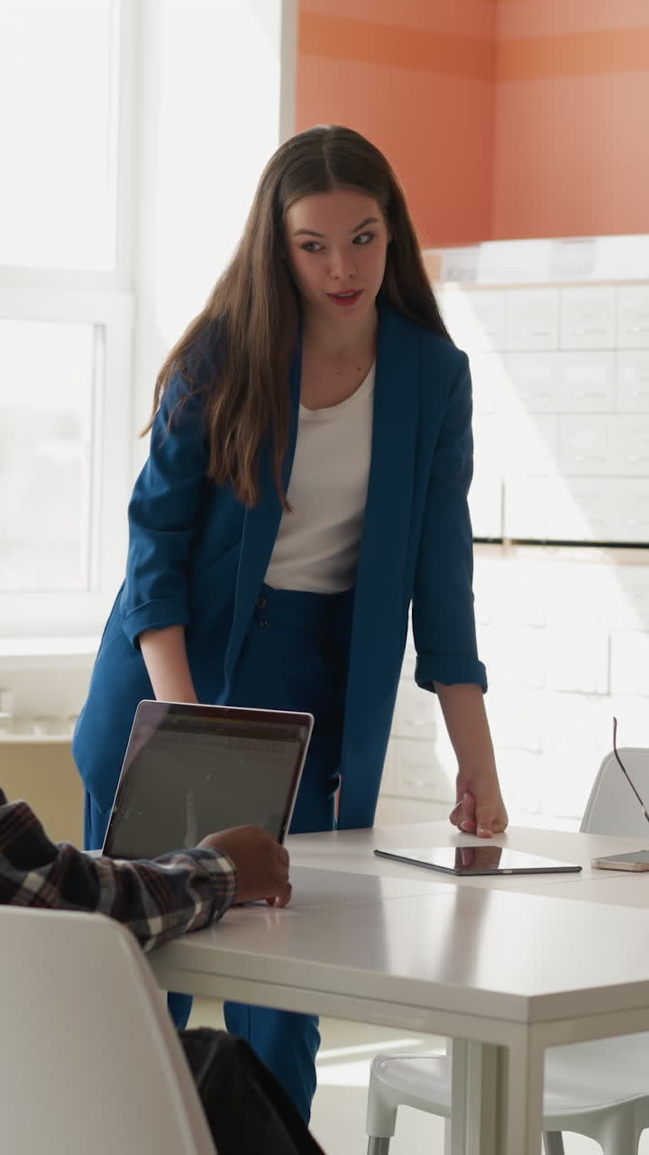 bibliotecario habla con los visitantes en la sala pública. mujer en traje de oficina informa al estudiante sobre el servicio en la biblioteca. instalación para la lectura de literatura e internet