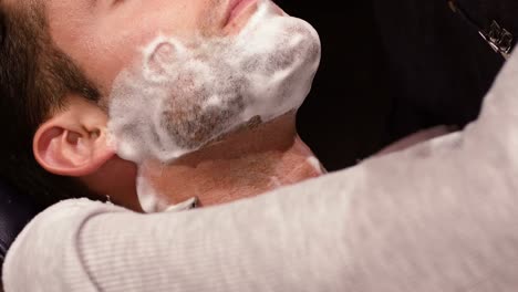 man getting his beard shaved with razor