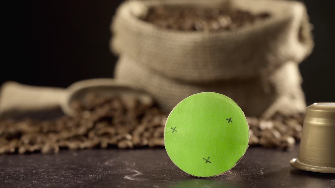 Capsula di caffè su green screen che rotola con chicchi di caffè