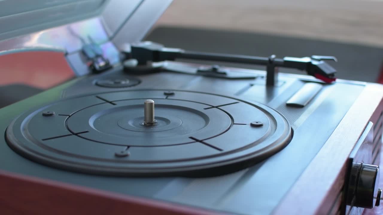 손은 비닐 레코드 플레이어 팔을 들고 그 자리에 놓습니다.