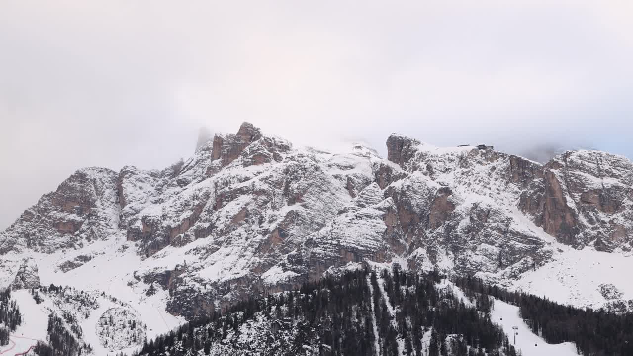 Ampia veduta panoramica cinematografica di una cresta montuosa innevata nelle Dolomiti sotto un luminoso cielo invernale.