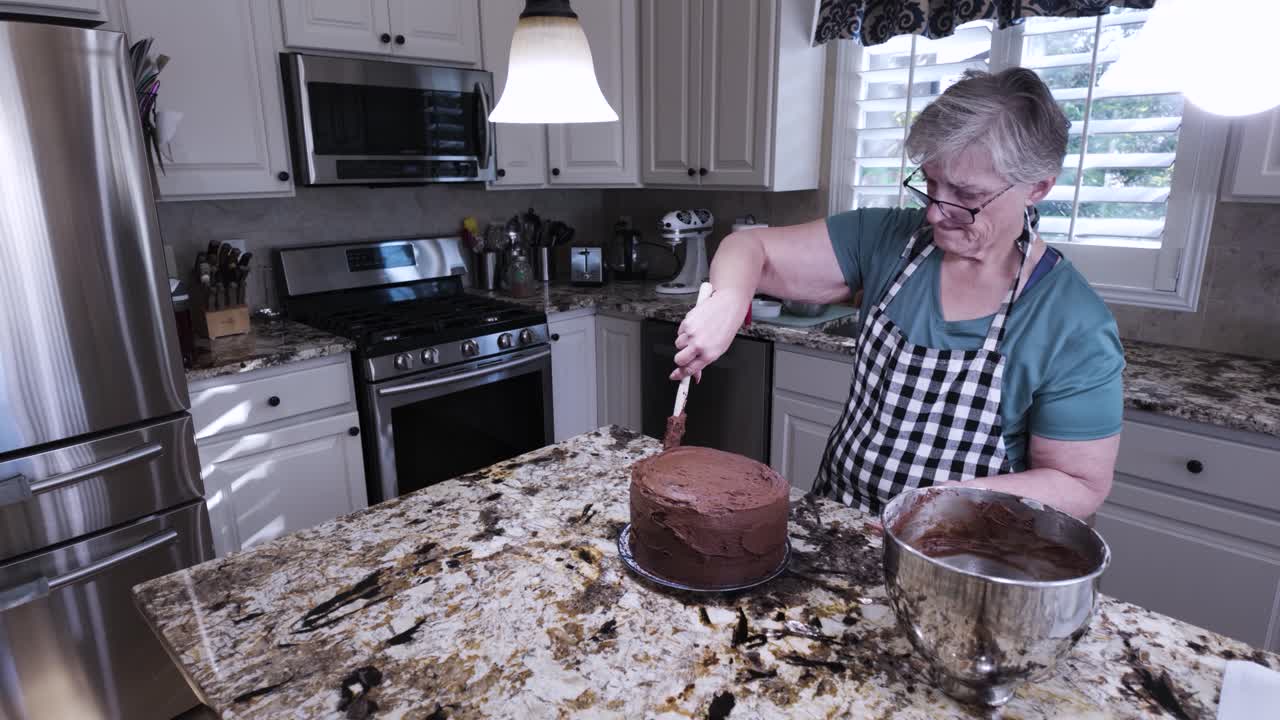 Nonna anziana che glassa e livella una torta al cioccolato