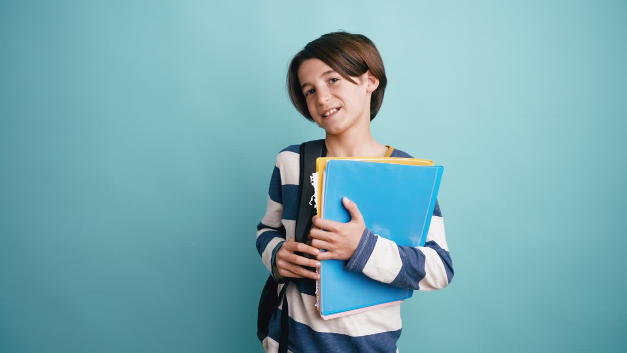 Giovane studente che sorride e tiene in mano materiale scolastico in studio