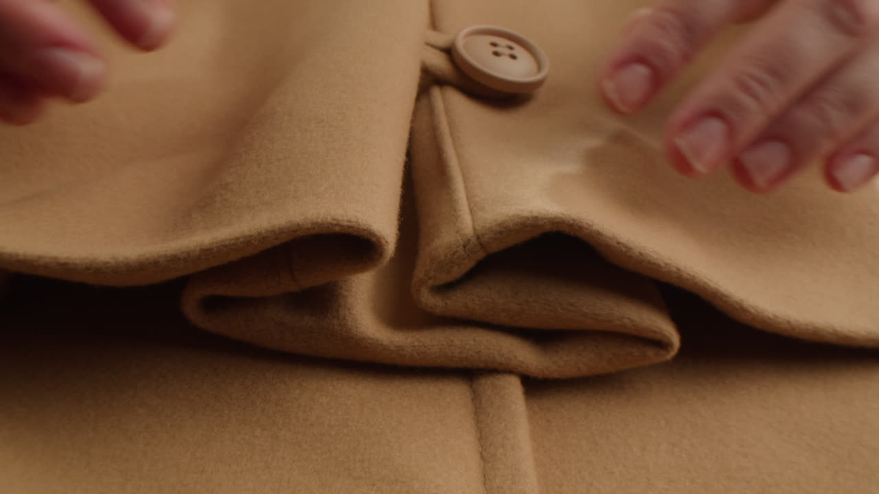 Close-up Mantel Beige dengan Tangan dan Kancing