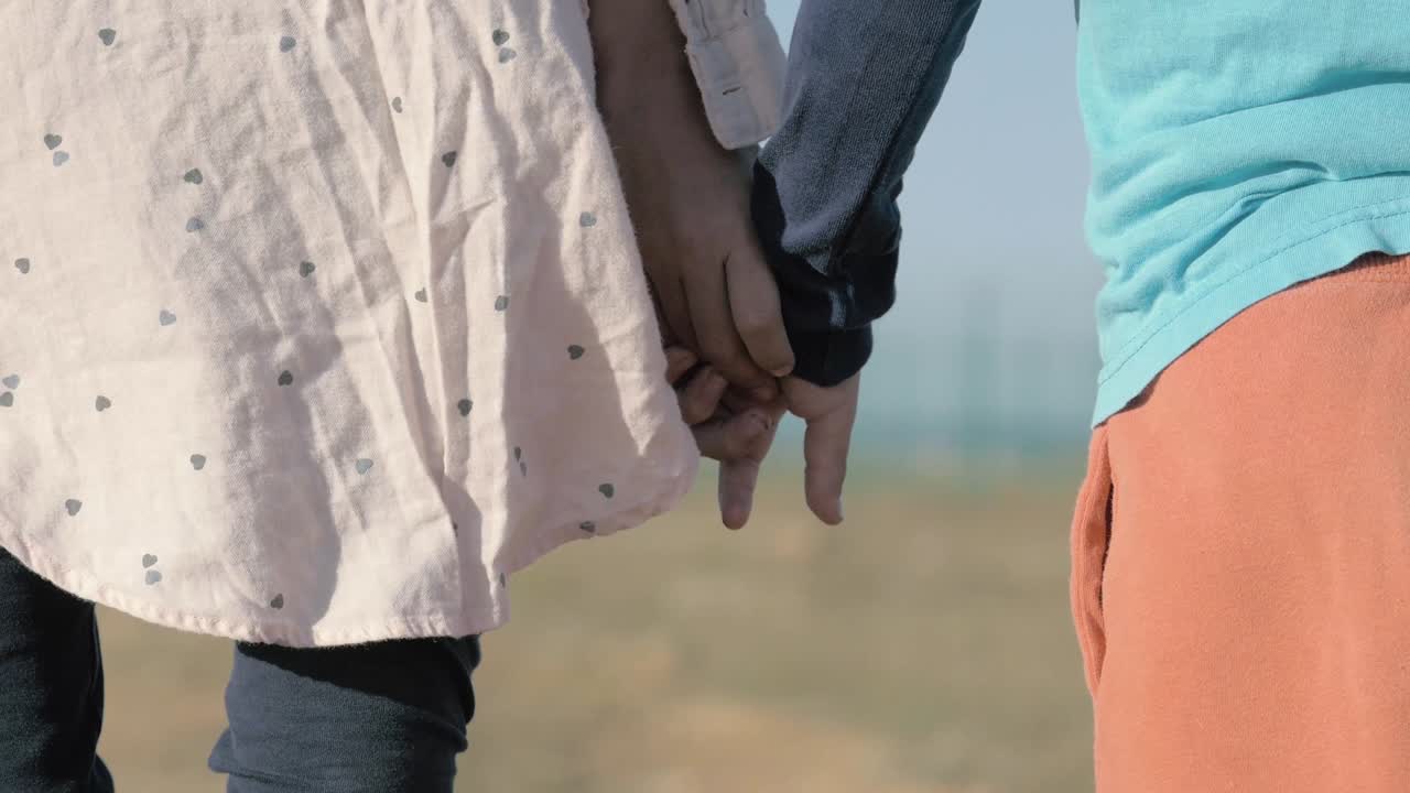 close-up children's hands holding each other. illegals Gypsies kids from dysfunctional family stand alone in field. Arabs refugees from middle East emigrate to Europe