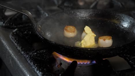 der koch fügt der pfanne mit muscheln butter hinzu