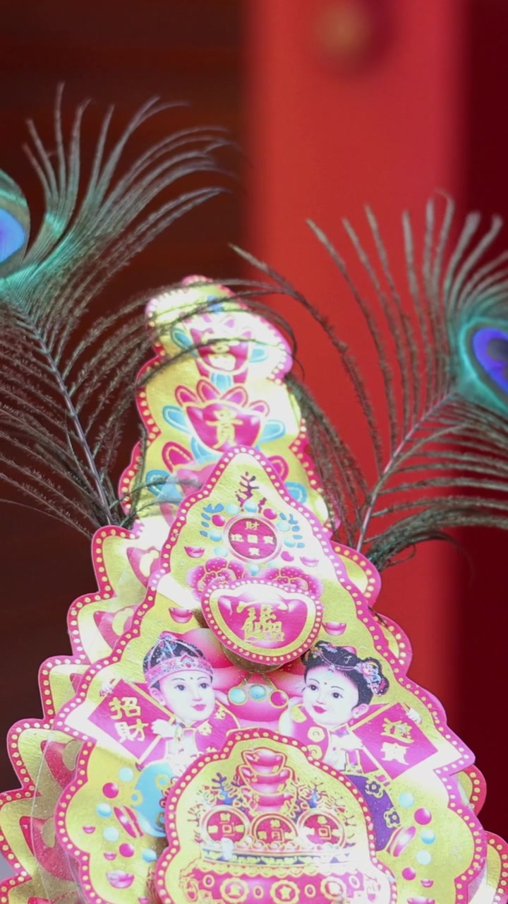 Um objeto cultural decorativo vibrante com penas de pavão move-se ligeiramente contra um fundo vermelho