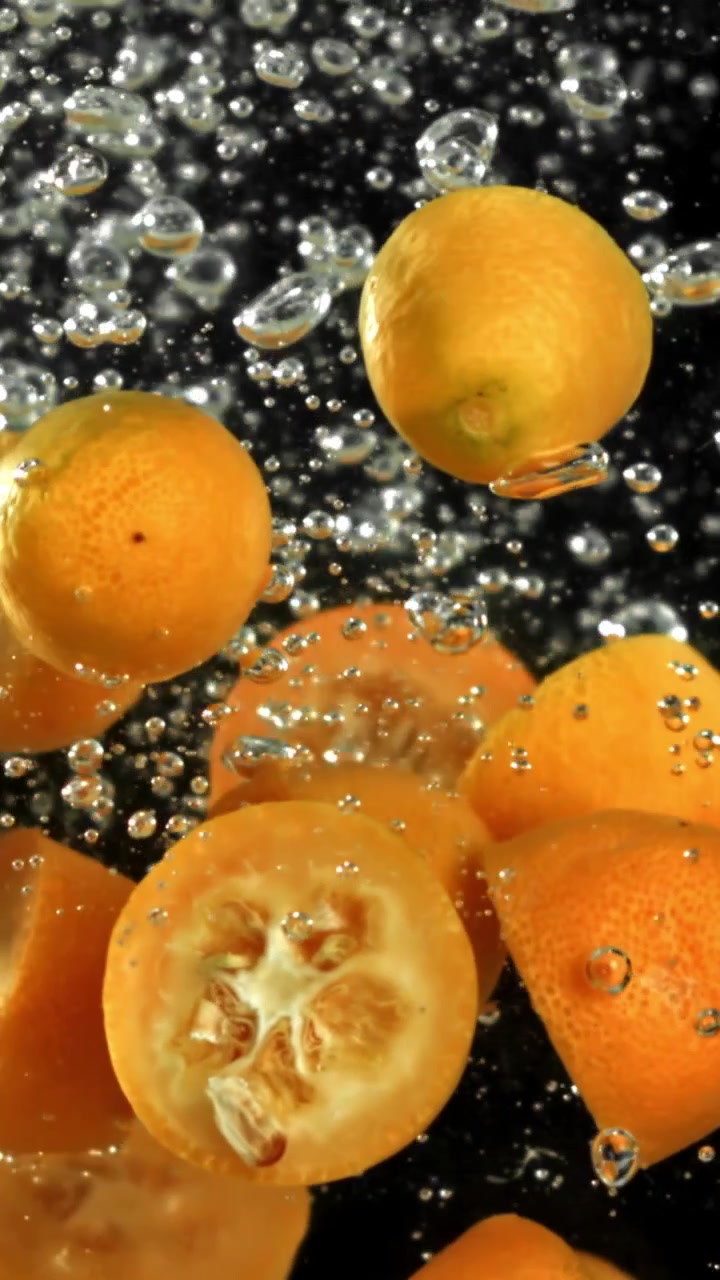 Frische Kumquats und Hälften in sprudelndem Wasser