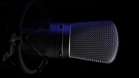 video vertical de 4k, micrófono de estudio profesional en una plataforma giratoria, fondo negro