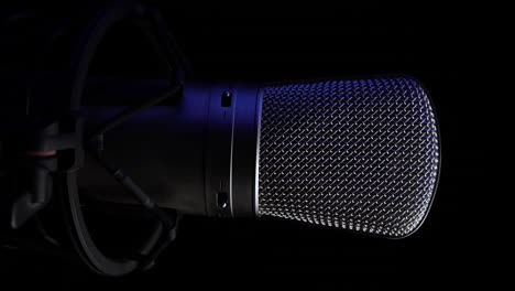 vertical 4k video, professional studio microphone on spinning platform, black background